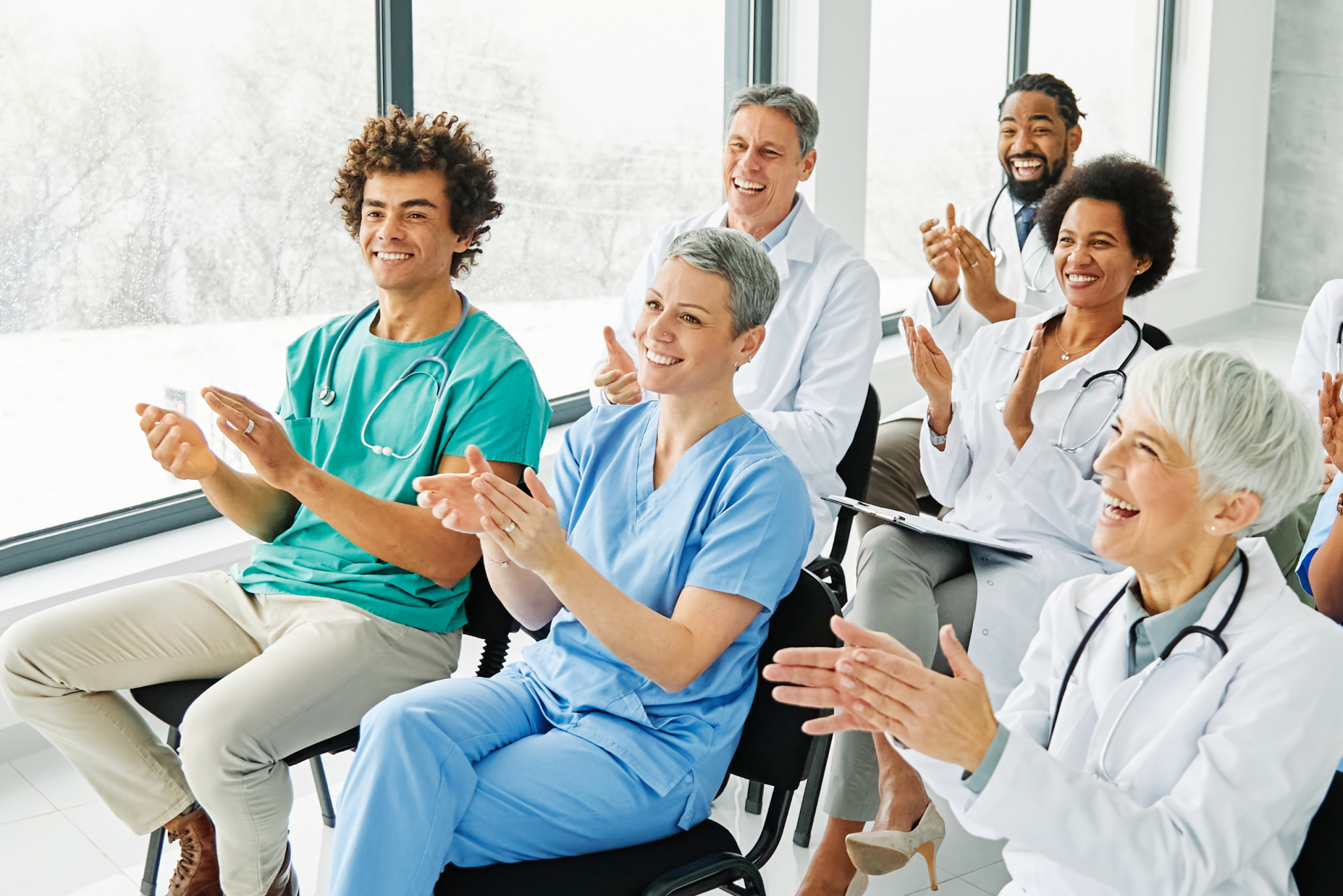 Seated group of smiling nurses and doctors applauding