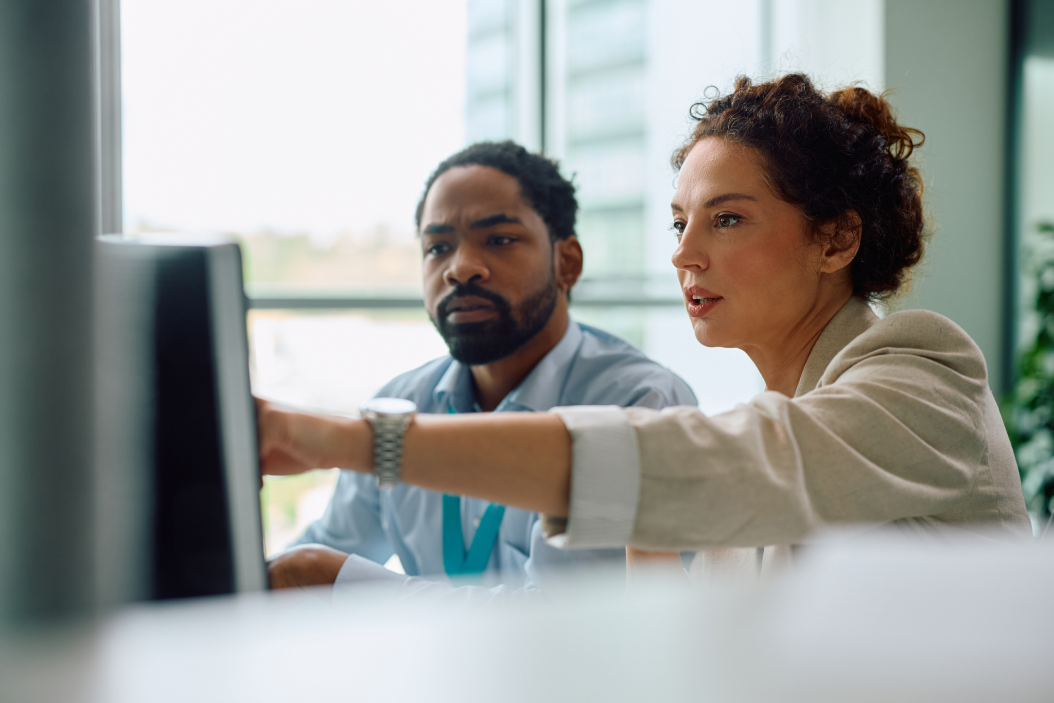 Two colleagues reviewing information on a computer monitor one pointing at the screen